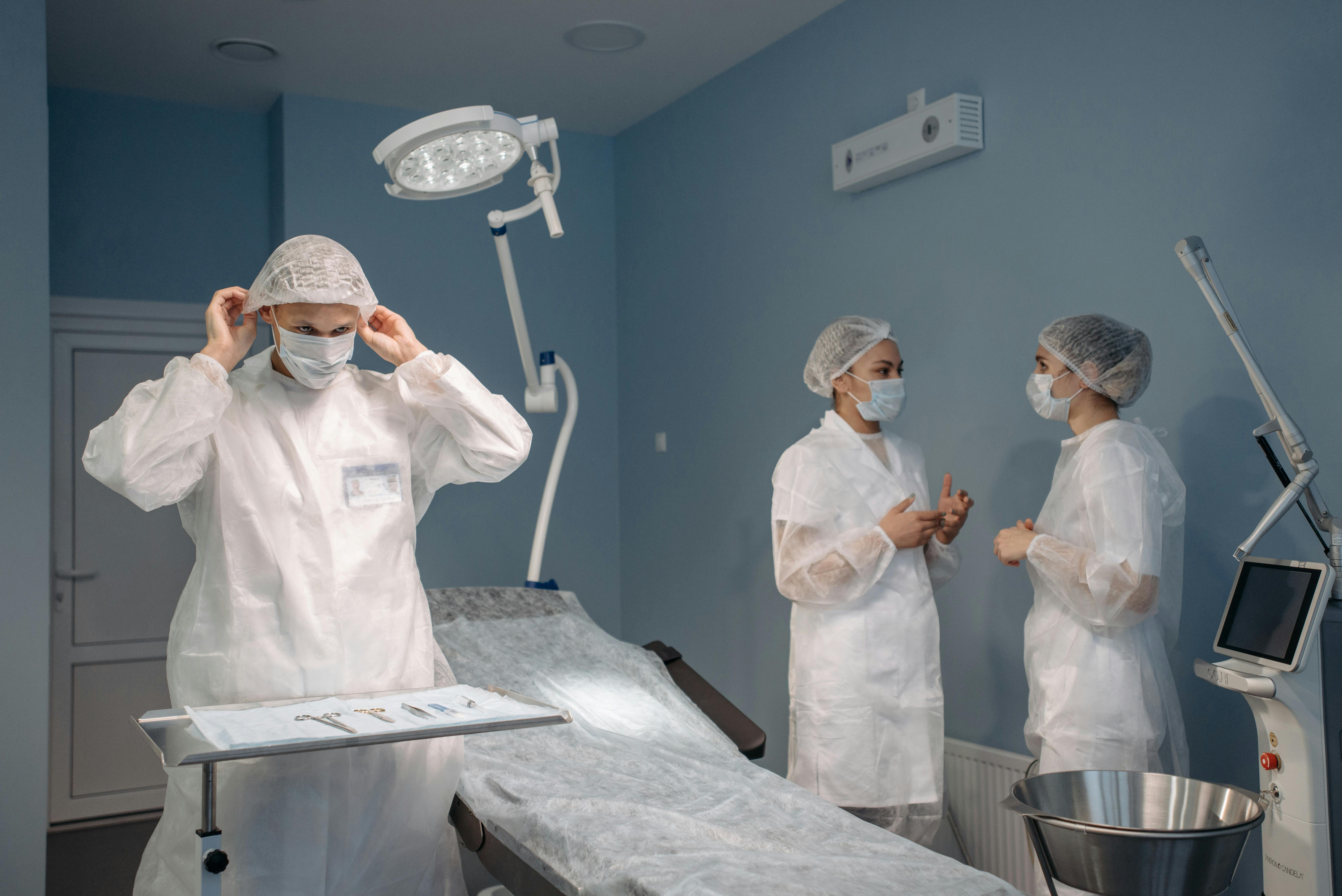 Healthcare professionals in PPE discussing surgical procedures in a modern operating room.